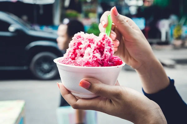Kırmızı şuruplu buzlu tatlılar ve doğal arka planda el ele tutuşan kadınlarda tatlı süt.
