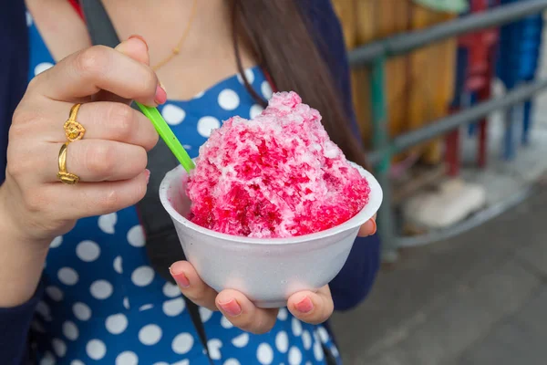 Kırmızı şuruplu buzlu tatlılar ve doğal arka planda el ele tutuşan kadınlarda tatlı süt.