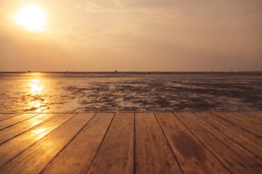 Ahşap zemin, günbatımı arka planında su düştüğünde denize doğru uzanıyor.