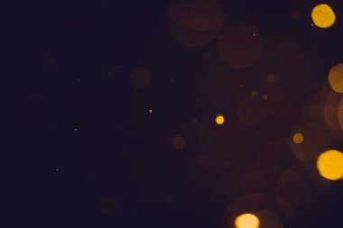 Siyah arkaplanda koyu soyut altın bokeh parıltısı