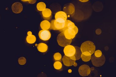 Siyah arkaplanda koyu soyut altın bokeh parıltısı