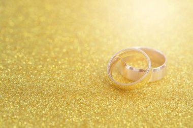 Altın yüzükler, gelin ve damadın alyansları beyaz, eski ahşap arka planda.