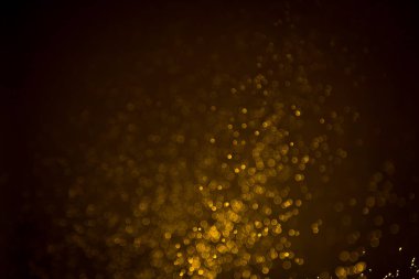 Siyah arkaplanda koyu soyut altın bokeh parıltısı