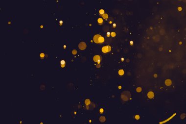 Siyah arkaplanda koyu soyut altın bokeh parıltısı