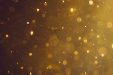 Siyah arkaplanda koyu soyut altın bokeh parıltısı