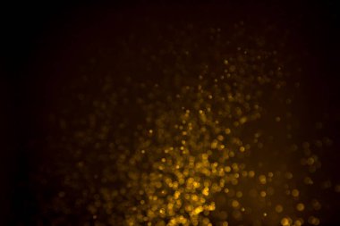 Siyah arkaplanda koyu soyut altın bokeh parıltısı