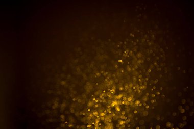 Siyah arkaplanda koyu soyut altın bokeh parıltısı