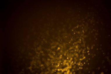 Siyah arkaplanda koyu soyut altın bokeh parıltısı