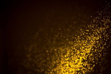 Siyah arkaplanda koyu soyut altın bokeh parıltısı