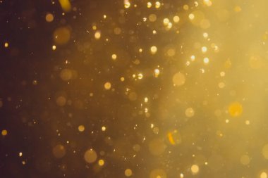 Siyah arkaplanda koyu soyut altın bokeh parıltısı