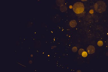 Siyah arkaplanda koyu soyut altın bokeh parıltısı