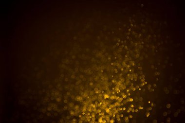 Siyah arkaplanda koyu soyut altın bokeh parıltısı