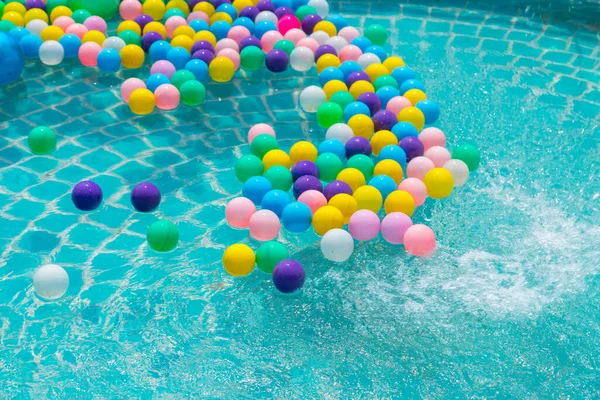 Yüzme havuzunda turkuaz ışığı yansıtan renkli toplar.