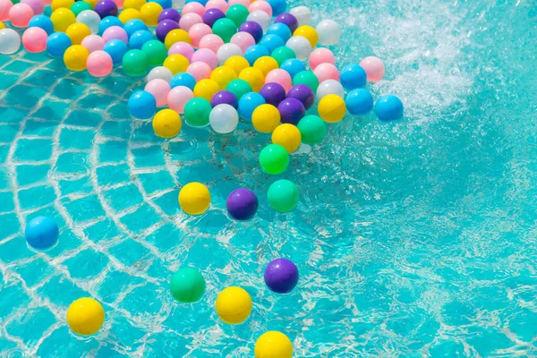 Yüzme havuzunda turkuaz ışığı yansıtan renkli toplar.