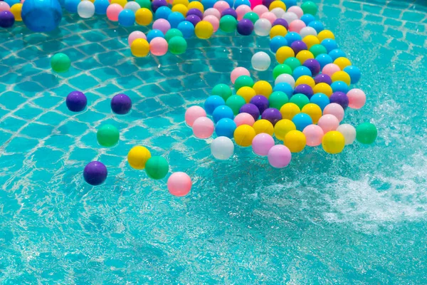 Yüzme havuzunda turkuaz ışığı yansıtan renkli toplar.
