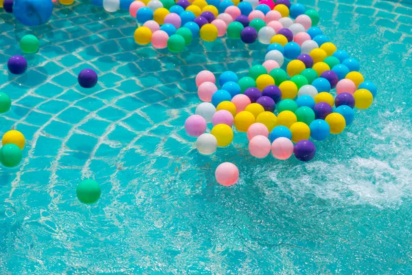 Yüzme havuzunda turkuaz ışığı yansıtan renkli toplar.