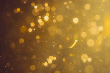 Siyah arkaplanda koyu soyut altın bokeh parıltısı