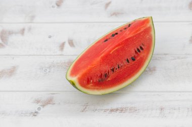 Kırmızı karpuz beyaz desenli ahşap bir zemine yerleştirilir, bol suyla birlikte meyve. Isıyı serbest bırakmaya yardımcı olur
