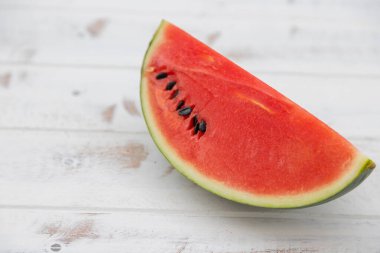 Kırmızı karpuz beyaz desenli ahşap bir zemine yerleştirilir, bol suyla birlikte meyve. Isıyı serbest bırakmaya yardımcı olur