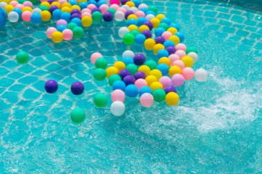 Yüzme havuzunda turkuaz ışığı yansıtan renkli toplar.