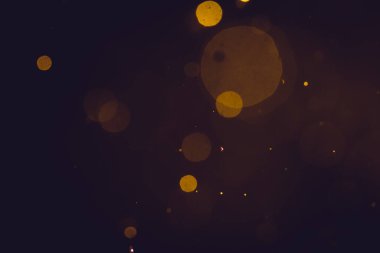 Siyah arkaplanda koyu soyut altın bokeh parıltısı