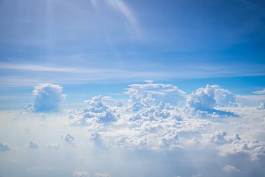 Gökyüzü ve yerden görünen bulutlar, açık renkli arka planlı bir uçaktan görüldü.