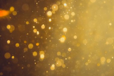 Siyah arkaplanda koyu soyut altın bokeh parıltısı