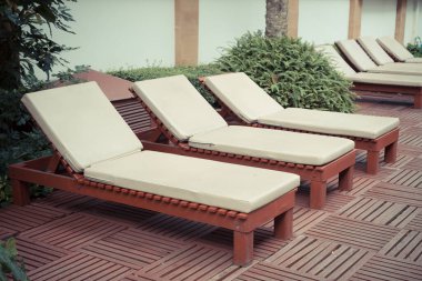 Havuz kenarındaki havuz sandalyelerinde ağaç var.