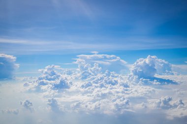 Gökyüzü ve yerden görünen bulutlar, açık renkli arka planlı bir uçaktan görüldü.