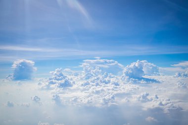 Gökyüzü ve yerden görünen bulutlar, açık renkli arka planlı bir uçaktan görüldü.