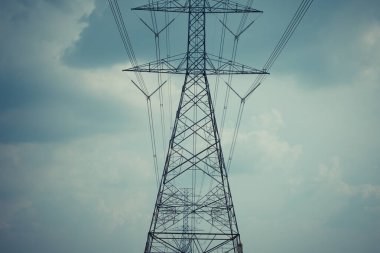 Yüksek voltaj direği kablosu ve bulutlu mavi gökyüzü.