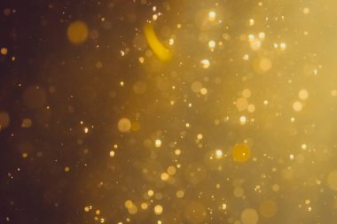 Siyah arkaplanda koyu soyut altın bokeh parıltısı