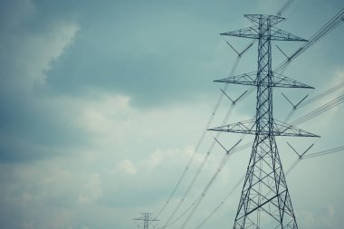 Yüksek voltaj direği kablosu ve bulutlu mavi gökyüzü.