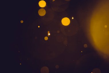 Siyah arkaplanda koyu soyut altın bokeh parıltısı