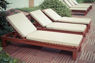 Havuz kenarındaki havuz sandalyelerinde ağaç var.