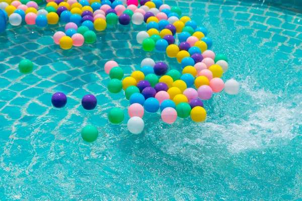 Yüzme havuzunda turkuaz ışığı yansıtan renkli toplar.