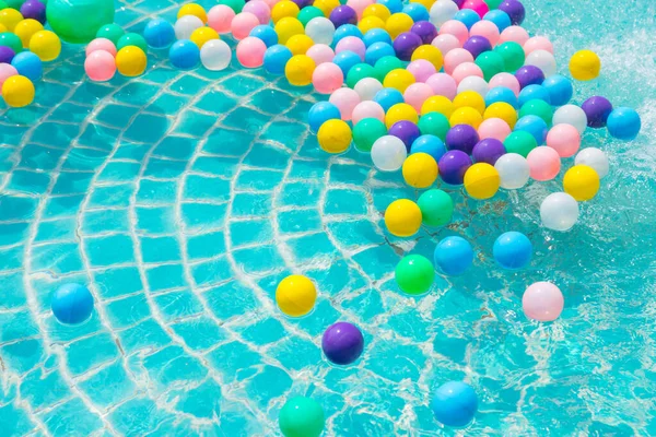Yüzme havuzunda turkuaz ışığı yansıtan renkli toplar.