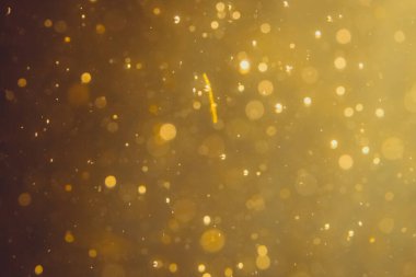 Siyah arkaplanda koyu soyut altın bokeh parıltısı