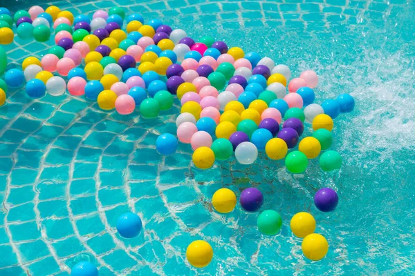 Yüzme havuzunda turkuaz ışığı yansıtan renkli toplar.