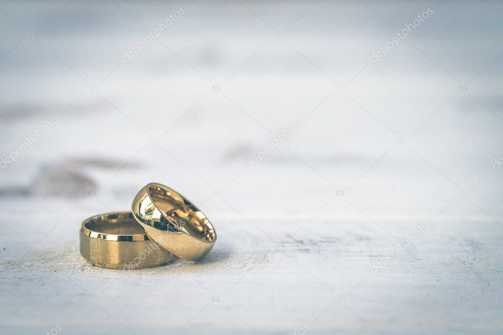 Golden rings, wedding rings of the bride and groom on white vintage wooden background