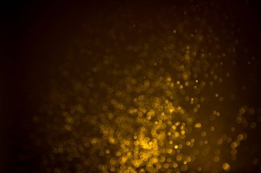 Siyah arkaplanda koyu soyut altın bokeh parıltısı