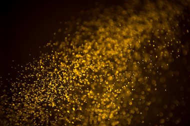 Siyah arkaplanda koyu soyut altın bokeh parıltısı