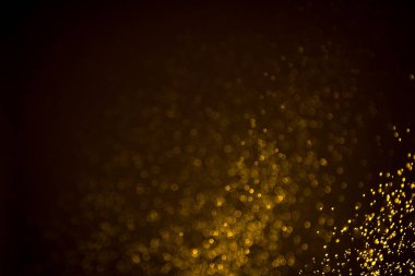 Siyah arkaplanda koyu soyut altın bokeh parıltısı
