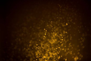 Siyah arkaplanda koyu soyut altın bokeh parıltısı