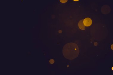 Siyah arkaplanda koyu soyut altın bokeh parıltısı