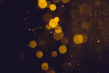 Siyah arkaplanda koyu soyut altın bokeh parıltısı