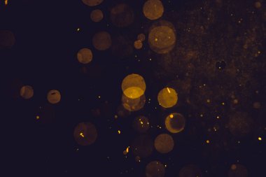 Siyah arkaplanda koyu soyut altın bokeh parıltısı