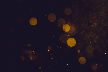 Siyah arkaplanda koyu soyut altın bokeh parıltısı