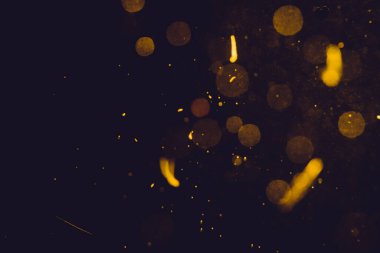 Siyah arkaplanda koyu soyut altın bokeh parıltısı