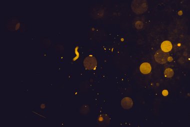 Siyah arkaplanda koyu soyut altın bokeh parıltısı
